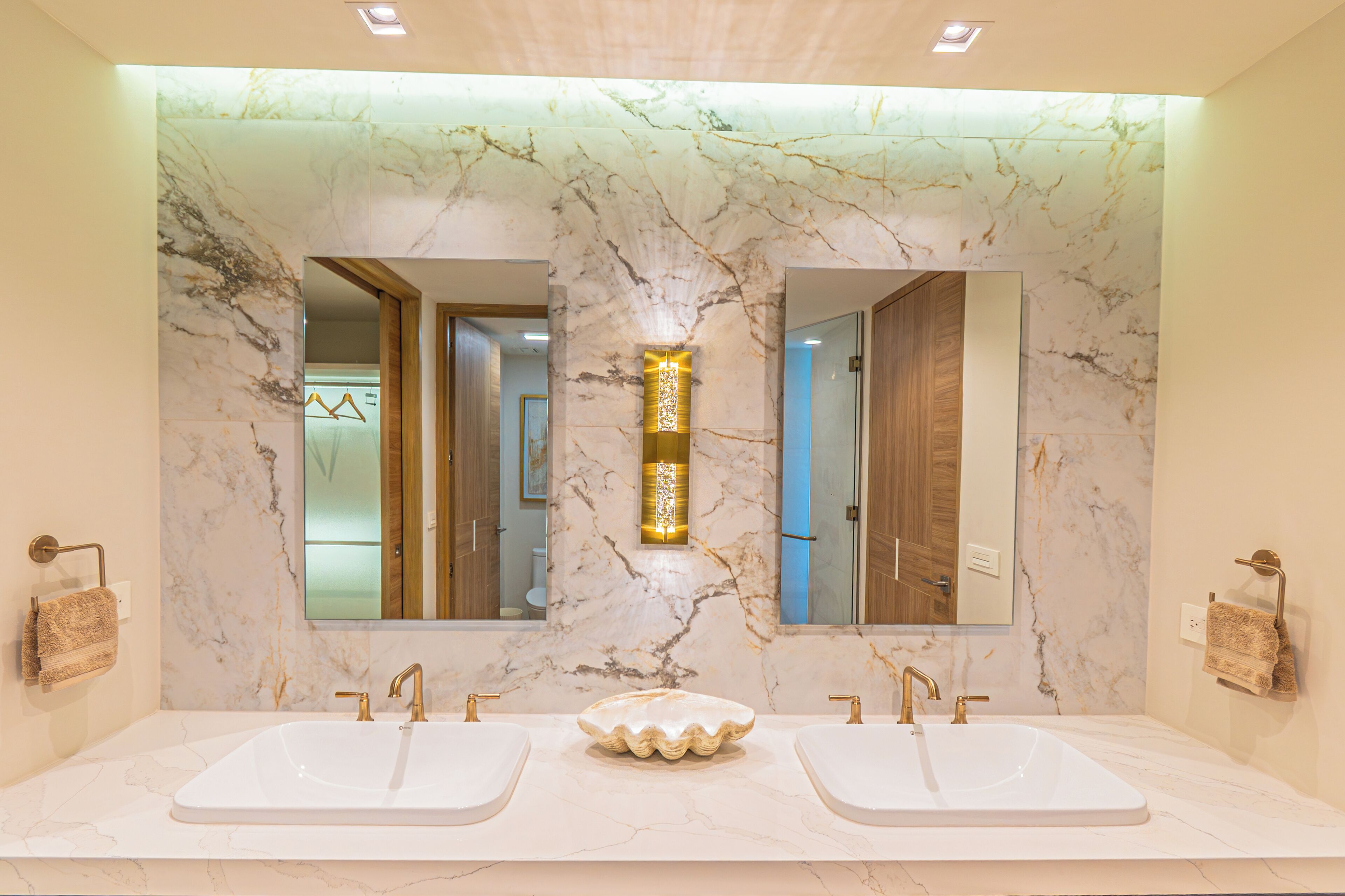A bathroom with two sinks, marble walls, and a central light fixture.