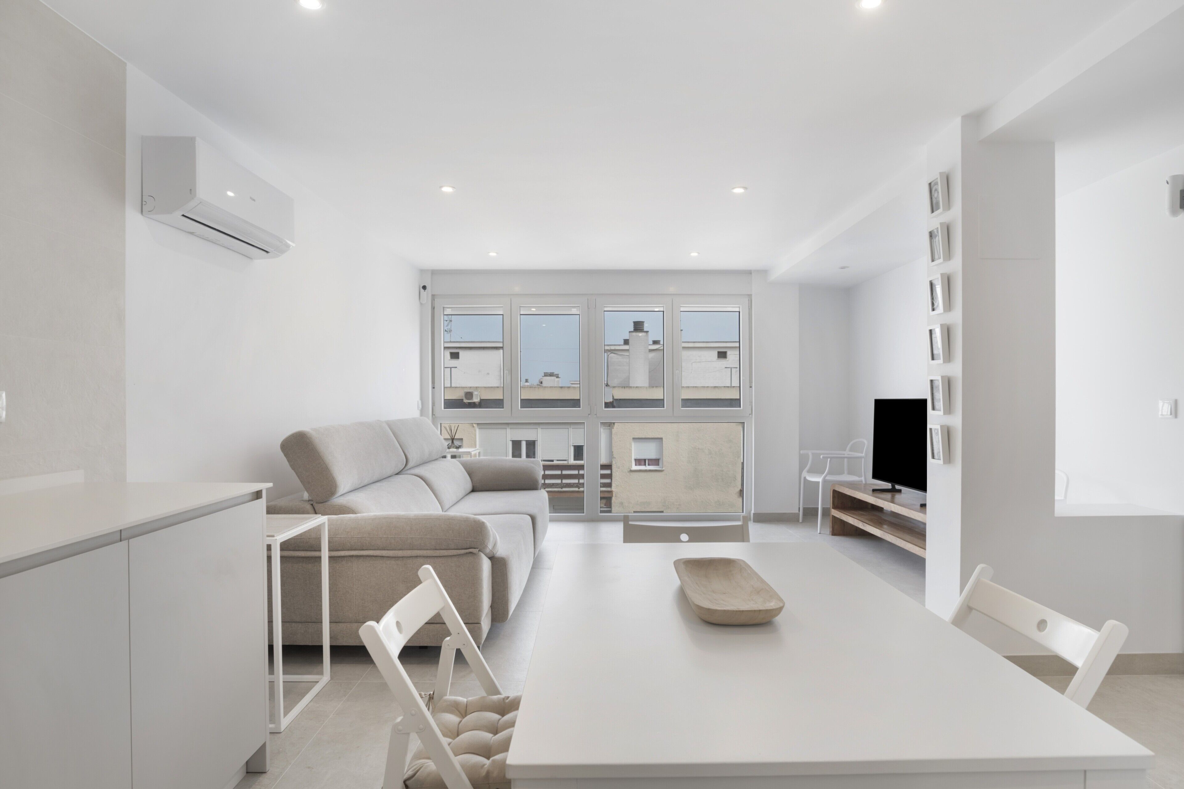 A modern living room with a sofa, a dining table, and a TV.