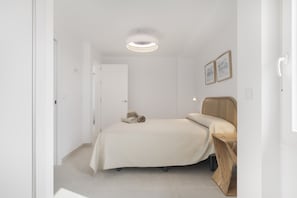 A bedroom with a bed, a ceiling light, a door, and a wall-mounted picture.