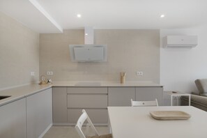 A modern kitchen with a built-in microwave, a small dining table, and a white chair.