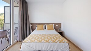 A hotel room with a bed, a nightstand, a glass door leading to a balcony, and a chair. - Property In A Holiday Village 'Quinta Da Pedra Caldeira B' with Mountain View and Air Conditioning (Armamar)