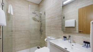 A modern bathroom with a glass shower enclosure, a toilet, a sink with a mirror, and a wooden cabinet. - Property In A Holiday Village 'Quinta Da Pedra Caldeira B' with Mountain View and Air Conditioning (Armamar)