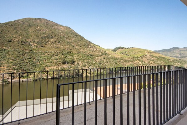 A balcony with a view of a river and hills.