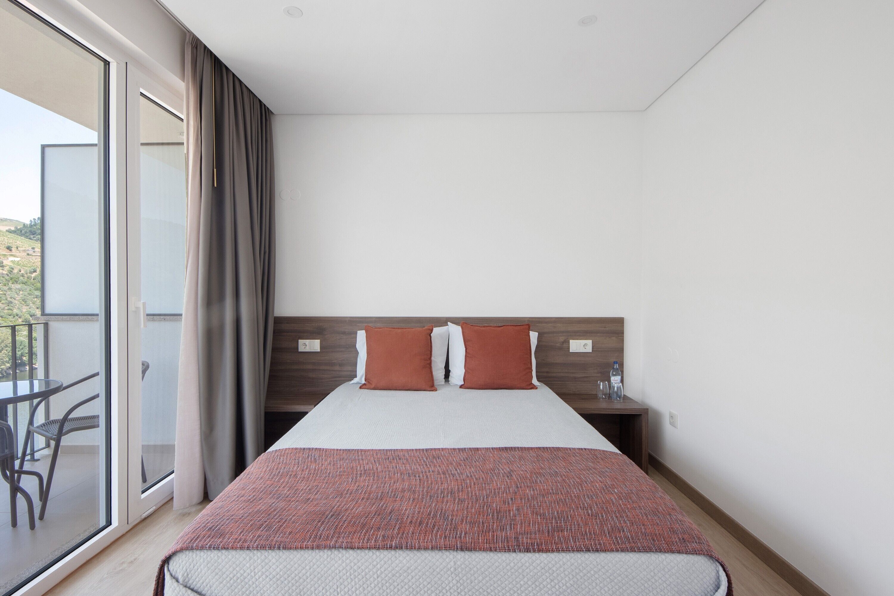 Une chambre d’hôtel avec un lit, une table de chevet, une table et une vue sur l’extérieur.