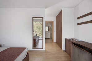Un dormitorio con cama, un escritorio de madera, un espejo y vistas a un balcón.