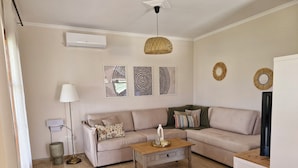 Un salon avec un canapé beige, une table basse en bois, une lampe et des œuvres d’art murales.