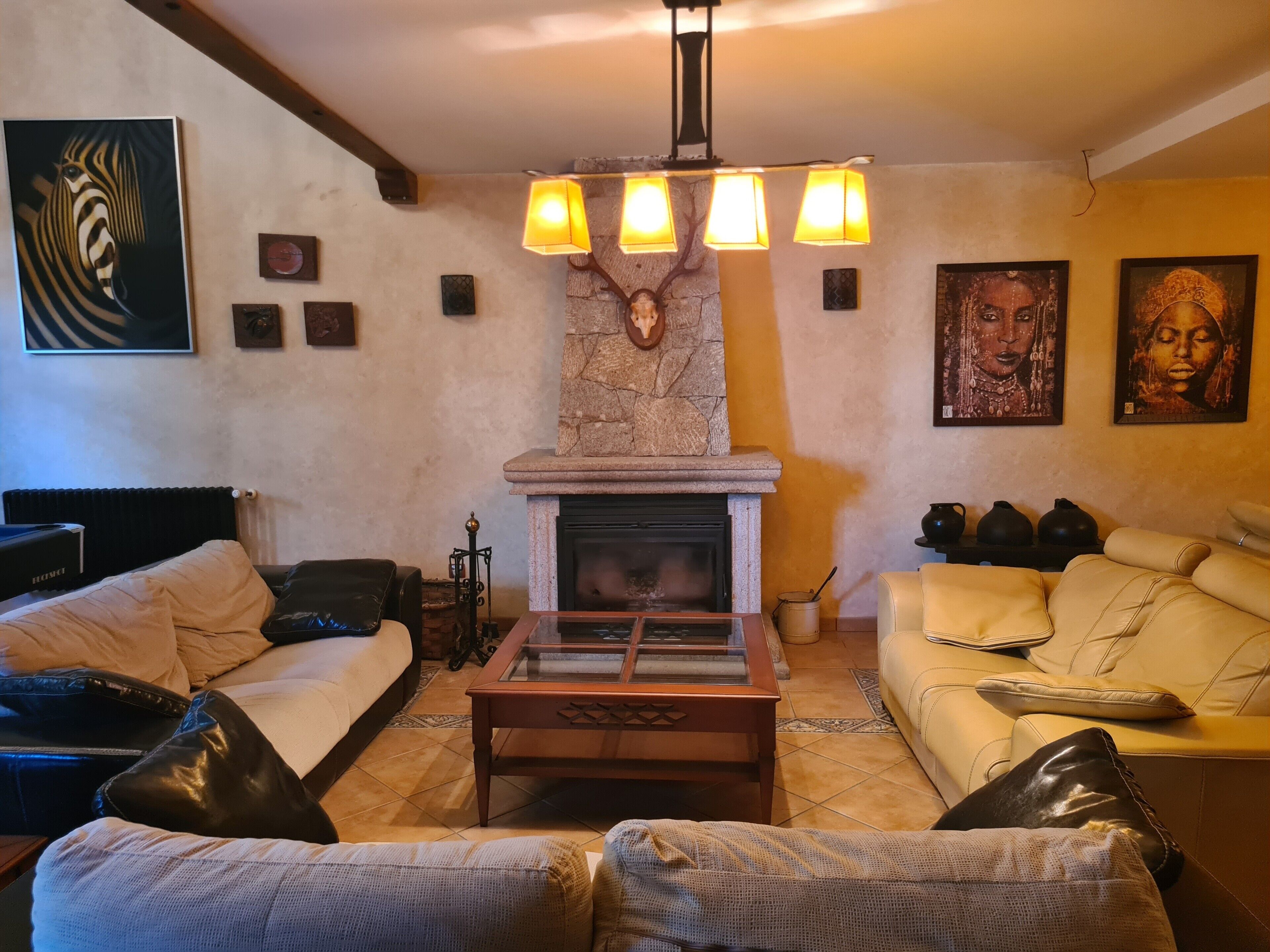 A living room with a fireplace, a sofa, a coffee table, and artwork on the walls.
