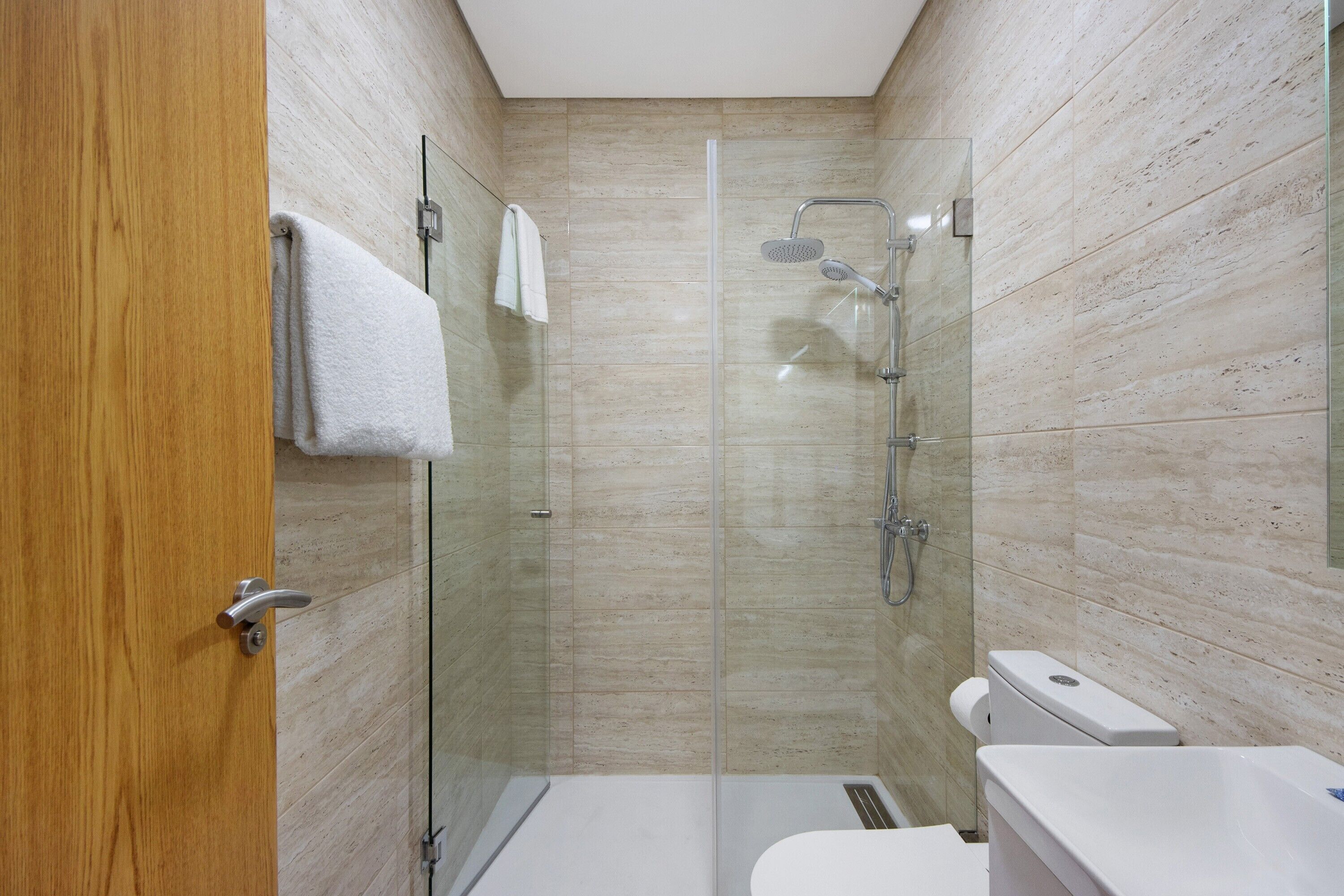 A modern bathroom with a glass shower enclosure, a toilet, and a sink.
