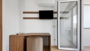 A modern room with a wooden desk, a television mounted on the wall, and a sliding glass door leading to an outdoor area. - Property In A Holiday Village 'Quinta Da Pedra Caldeira I' with Mountain View and Air Conditioning (Armamar)