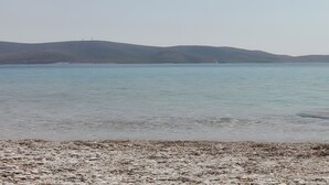 A calm body of water with a pebbly shore and distant hills. - Apartment 'Afroditi' with Sea View, Wi-Fi and Air Conditioning (Salamina)