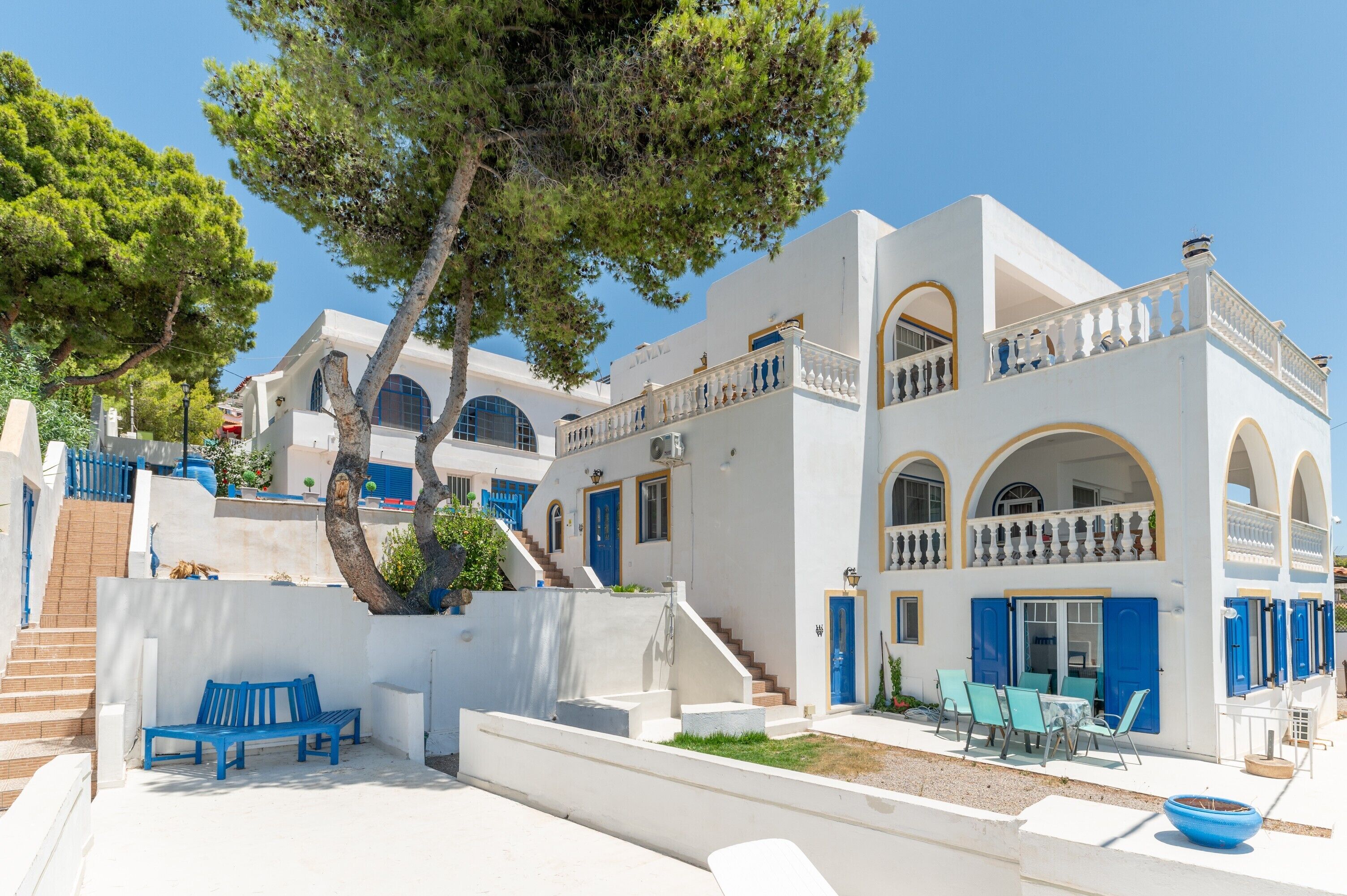 Un bâtiment blanc agrémenté de touches de bleu, avec un escalier et des sièges à l’extérieur.