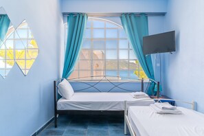 A room with a bed, a TV, and a window with curtains.