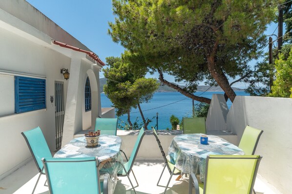A terrace with two tables and chairs, overlooking a coastal view.