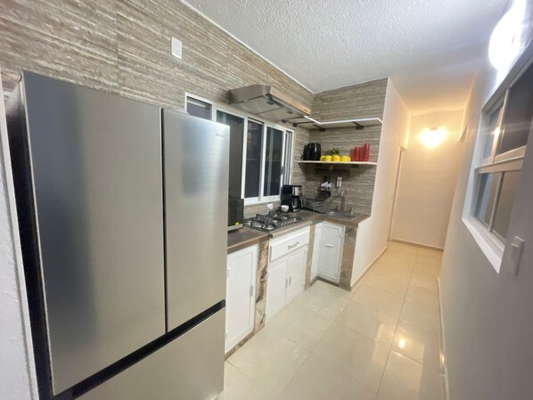 A modern kitchen with stainless steel appliances, white cabinets, and a tiled floor.