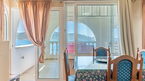Ein Zimmer mit Esstisch, Stühlen, Blick durch eine Glastür und einem Vorhang.