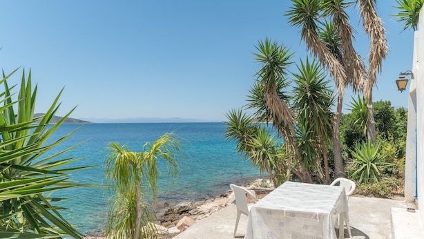 Une terrasse en bord de mer, avec une table et des chaises, donnant sur l’océan.