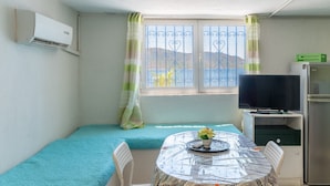 Une pièce comprenant un lit, une table avec un vase de fleurs, une télévision et un réfrigérateur.