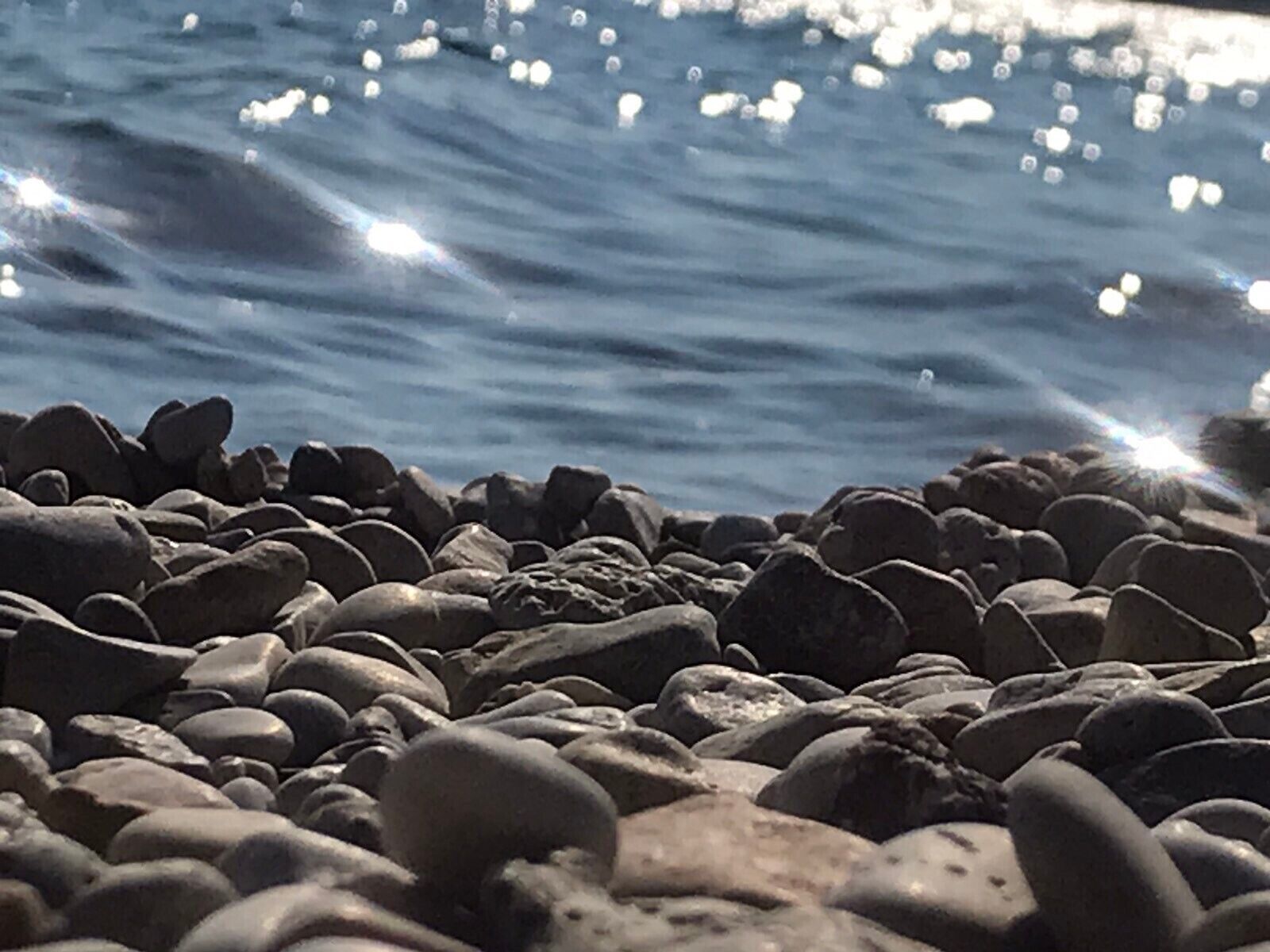 Una costa rocosa con el agua reflejando la luz del sol.