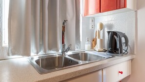 Eine Küche mit zwei Edelstahl-Spülen, einer Kaffeemaschine und einer Flasche Geschirrspülmittel.