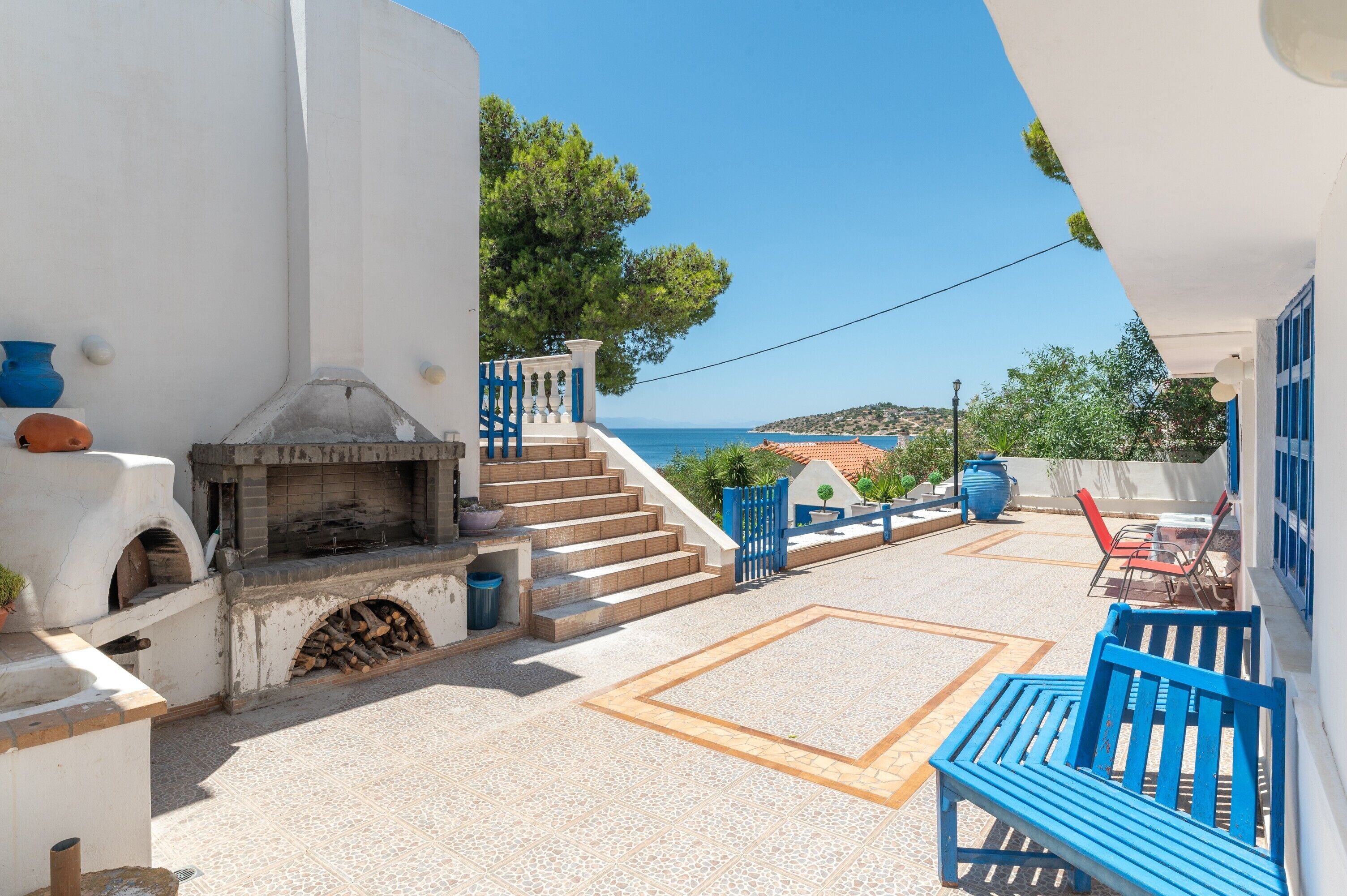 Un patio con un camino in pietra, posti a sedere all'aperto e vista sul mare.