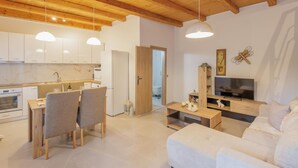 Ein modernes Interieur mit Holzboden, einem Essbereich, einem Wohnzimmer mit Sofa und Fernseher.