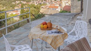 Eine Terrasse mit Tisch für Zwei, Blick auf eine Stadt mit Kirchturm und Steinboden.