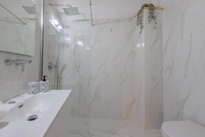 A modern bathroom with a glass-enclosed shower, a white marble sink, and a toilet.