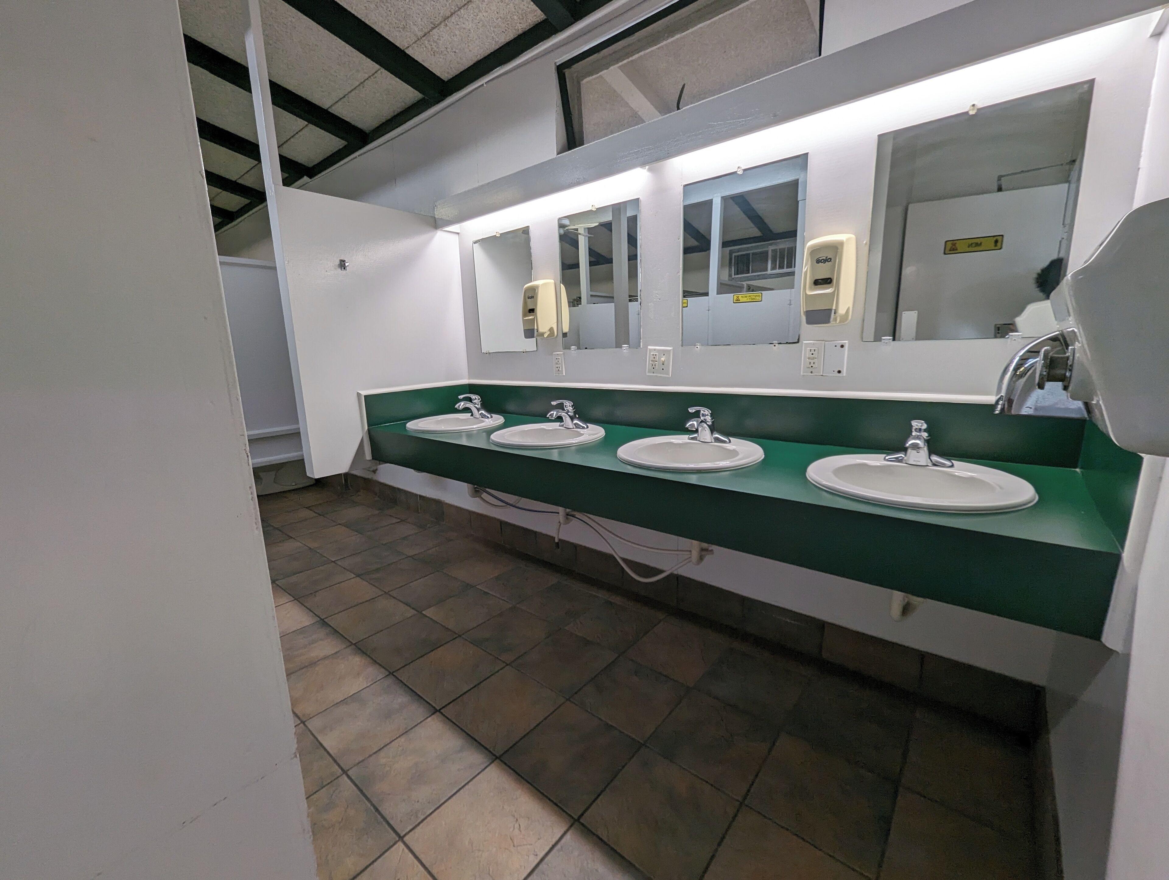 Baño con tres lavamanos, cada uno con un espejo encima.