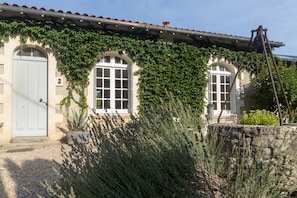 A building with arched windows, a white door, and a stone wall.
