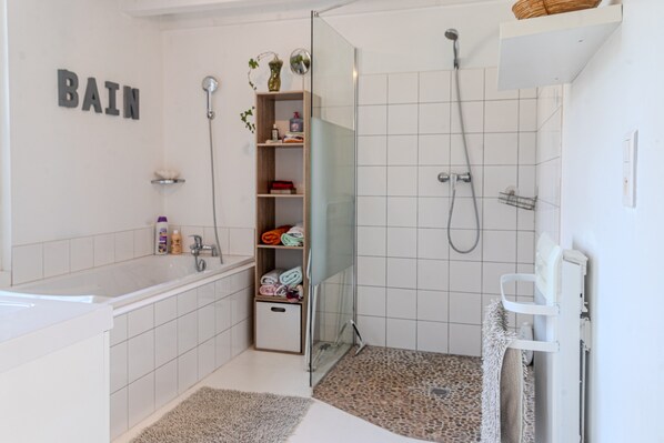 Un baño moderno con bañera, ducha y repisas con artículos de tocador.