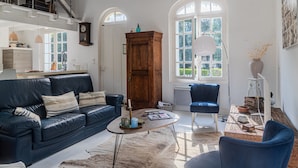 Ein geräumiges Wohnzimmer mit einem blauen Sofa, einem Holzschrank und einem großen Fenster.