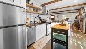 Una cucina moderna con elettrodomestici in acciaio inossidabile, scaffali in legno e un rustico camino in pietra.