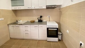 A compact kitchen with white cabinets, a stove, and a sink.