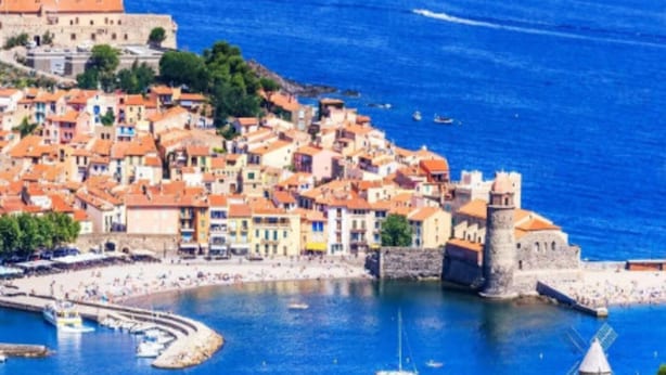 Une ville côtière dotée de bâtiments historiques, d’une structure fortifiée et d’un port de plaisance.