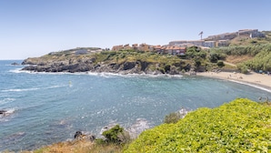 Une zone côtière avec des bâtiments construits sur une colline, une plage et la mer.