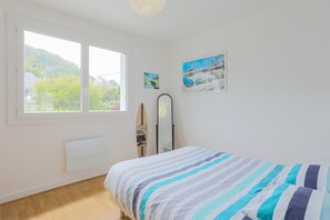 Une chambre avec un lit, une fenêtre, un radiateur et des œuvres d’art murales.