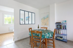 Un coin repas comprenant une table, des chaises, une bibliothèque et une carte accrochée au mur.