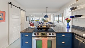 Une cuisine moderne dotée d’un îlot central, d’appareils électroménagers en acier inoxydable et de meubles de rangement bleus.