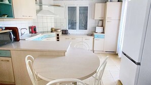 A compact kitchen with a central island, white cabinetry, and a tiled floor. - Holiday home for 6 people with pool in Lacanau Océan (LACANAU OCEAN)