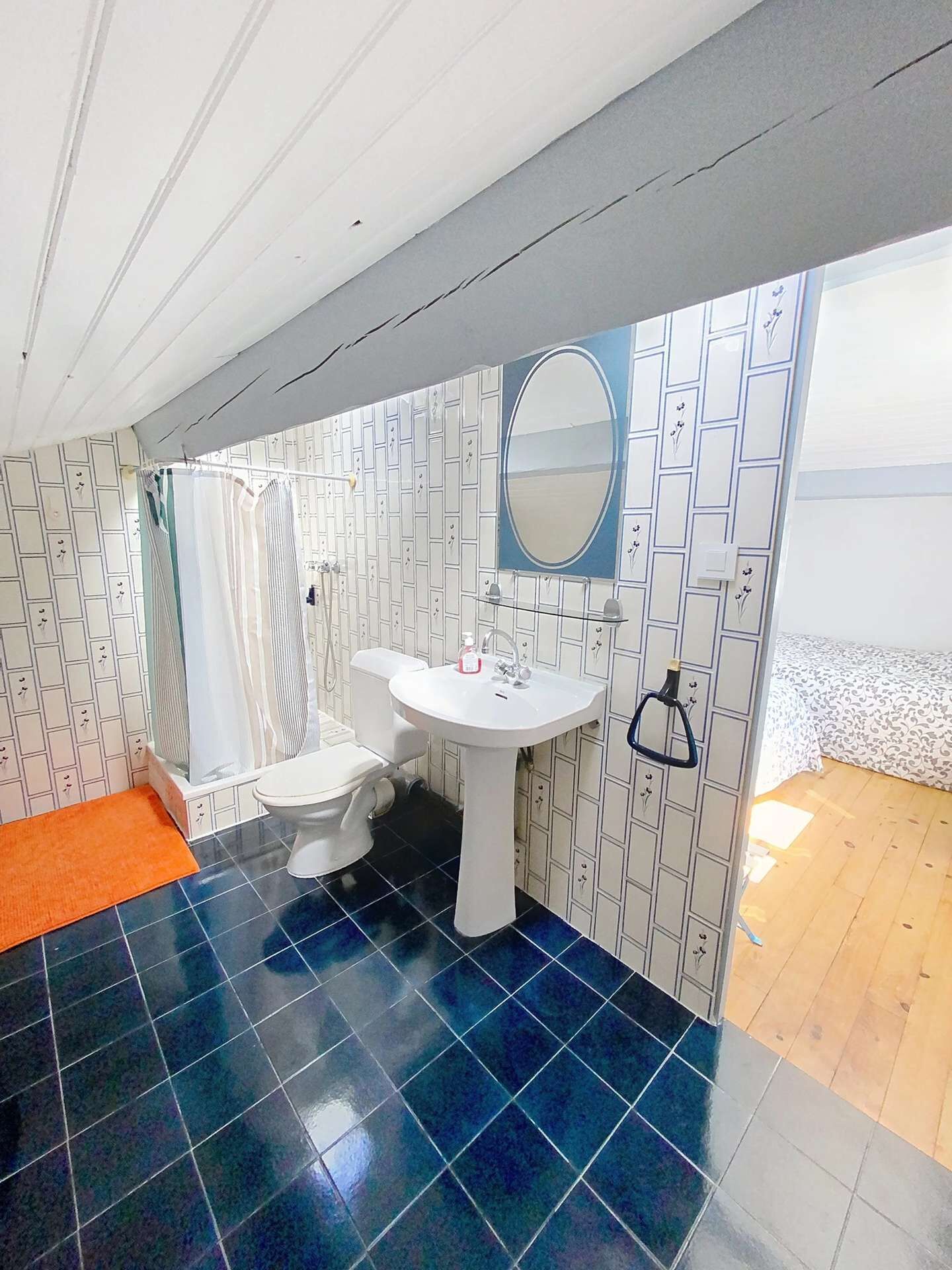 A bathroom with a white sink, a toilet, and a shower curtain. The floor is tiled in blue and white.