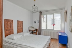 A bedroom with a bed, a desk, a chair, a radiator, and a window with a view. - Holiday Home 'Maison De Famille Paisible' with Private Terrace and Wi-Fi (Le Pouliguen)