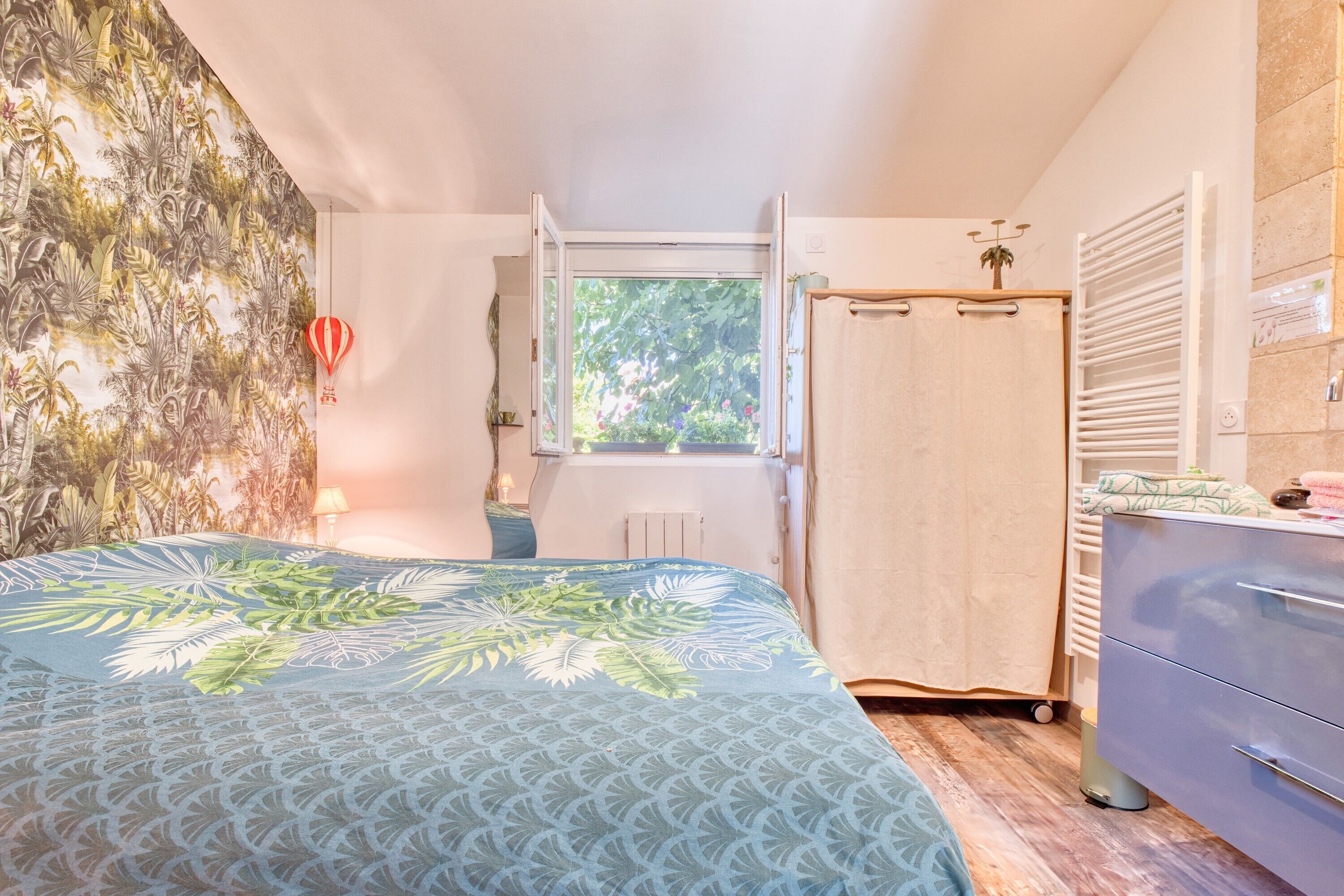 Une chambre à coucher avec un lit, une fenêtre, une armoire et un radiateur.
