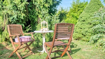 Deux chaises en bois avec des coussins, une petite table ronde et un miroir décoratif.