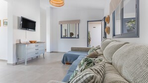 Un salon moderne avec un canapé, un téléviseur, une commode et une grande fenêtre.