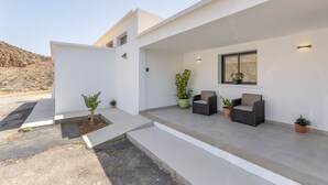 Un bâtiment moderne doté d’un patio couvert, d’un espace extérieur aménagé pour s’asseoir et de plantes en pot.