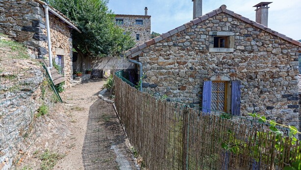 A narrow stone pathway leading to a rustic stone building with a wooden fence and a small window with shutters. - Le Bacci Country House with Mountain View, Private Garden & Wi-Fi (Vals-les-Bains)