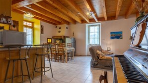 A dining area with a wooden ceiling, a piano, and a television. - Le Bacci Country House with Mountain View, Private Garden & Wi-Fi (Vals-les-Bains)