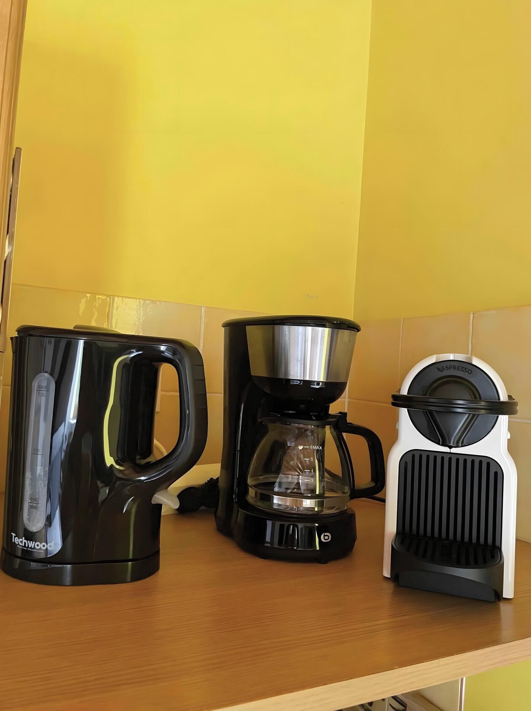 Una cuina amb un taulell, una cafetera, un brollador d'aigua i una màquina de Nespresso.