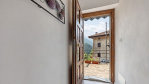 Un couloir menant à un balcon d’où l’on peut admirer une montagne et un bâtiment.