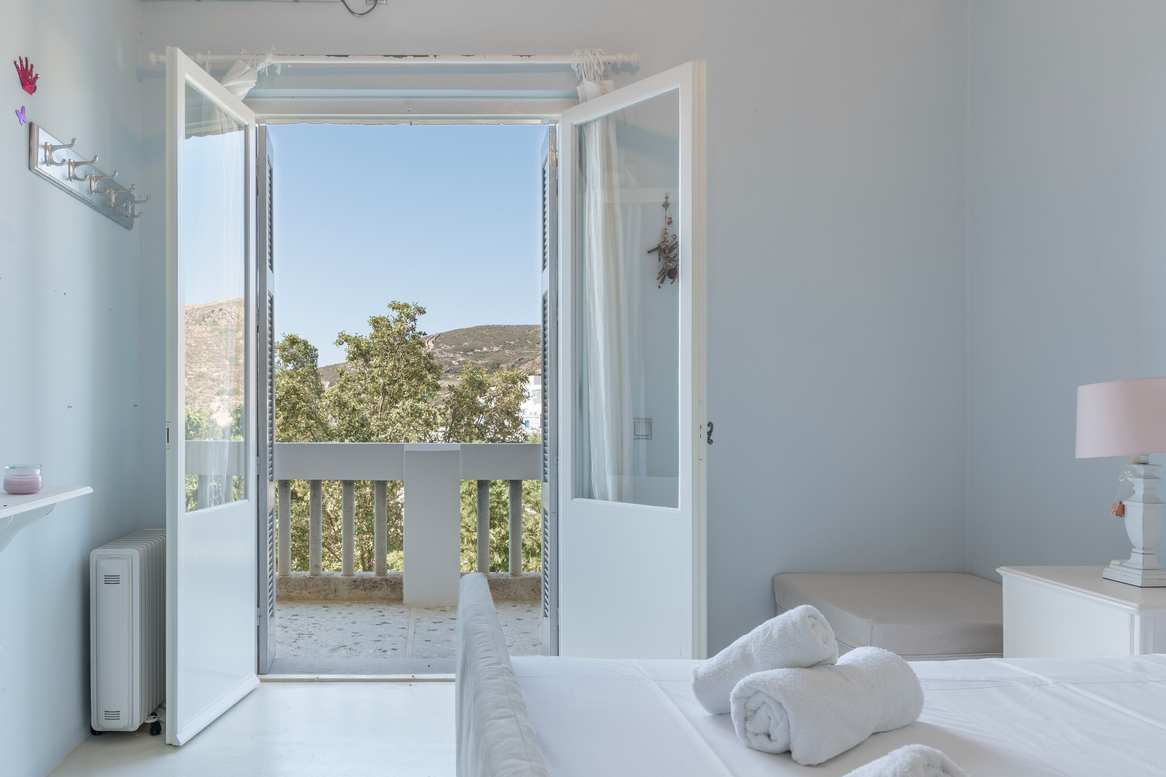 Ein Schlafzimmer mit Balkon, einem Bett, einem Nachttisch und Blick ins Freie.